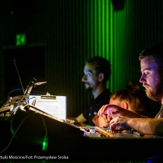 Koncert muzyki filmowej - Crushed Sounds BigBand - Kilku mężczyzn siedzi przy panelu i nadzoruje występ.  - Fot. Przemysław Sroka