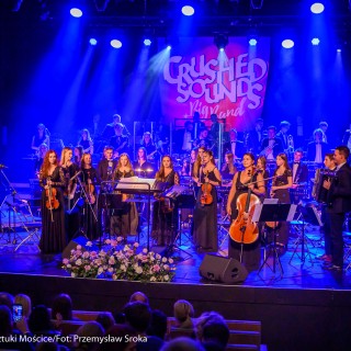 Koncert muzyki filmowej - Crushed Sounds BigBand - Orkiestra stoi na scenie, w rękach trzymają instrumenty, za nimi na ekranie wyświetla się napis "Crushed Sounds + Big Band". - Fot. Przemysław Sroka
