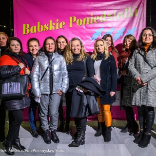 Babski Poniedziałek - To musi być miłość - Liczna grupa kobiet w kurtkach i płaszczach stoi przed różowym plakatem reklamującym wydarzenie "Babskie Poniedziałki" - Fot. Przemysław Sroka