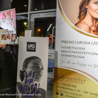 Babski Poniedziałek - To musi być miłość - Po lewej stronie rudowłosa kobieta trzyma w rękach ulotki reklamujące oferty Instytutu Medycyny Estetycznej. Po prawej stronie znajdują się dwa plakaty reklamowe Instytutu - Fot. Przemysław Sroka