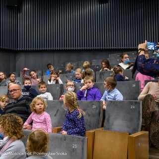 Teatr Młodych Widzów - "Miś Tymoteusz" - spektakl Teatru Rabcio - Po prawej stronie kobieta ubrana na granatowo robi zdjęcie dzieciom znajdującym się na widowni. Dzieci rozglądają się w różnych kierunkach.  - Fot. Przemysław Sroka