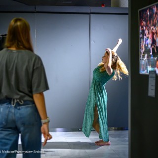 Wernisaż wystawy "Performance Dance" - Kobieta stoi w holu i patrzy na poruszającą się tancerkę. - Fot: Przemysław Sroka