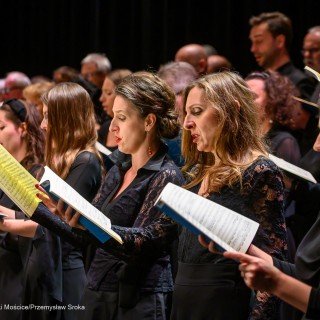 Requiem Mozarta - koncert Orkiestry i Chóru Filharmonii Krakowskiej - Kobiety i mężczyźni stoją obok siebie, trzymają w dłoniach śpiewniki i śpiewają. - Fot: Przemysław Sroka