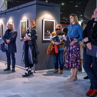 "Women" - wystawa fotografii Doroty Góreckiej - Kobiety i mężczyźni stoją w holu. Za nimi znajduje się wystawa fotografii. - Fot: Przemysław Sroka