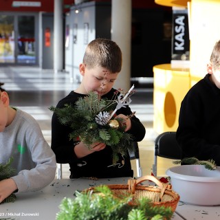 „Stroiki bożonarodzeniowe” warsztaty dla grup zorganizowanych przedszkolnych i wczesnoszkolnych - Trzej chłopcy w skupieniu ozdabiają swoje stroiki. - fot. Michał Żurowski